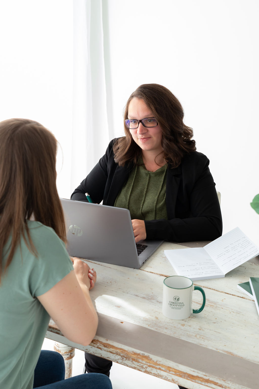 Christina Grootveld geeft cursus in Hoog Dividend beleggen, tijdens een persoonlijk gesprek met een deelnemer aan tafel met laptop en notities.