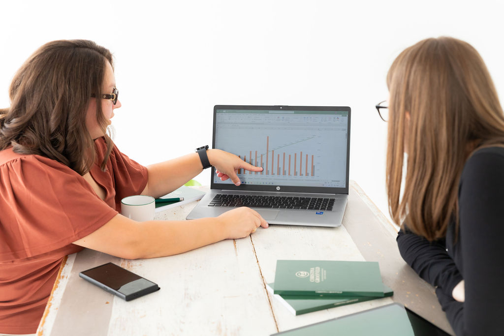 Coach Christina Grootveld legt een vrouw uit hoe Hoog Dividend beleggen werkt aan de hand van dividendgrafieken op laptop – persoonlijke begeleiding in Nederland.